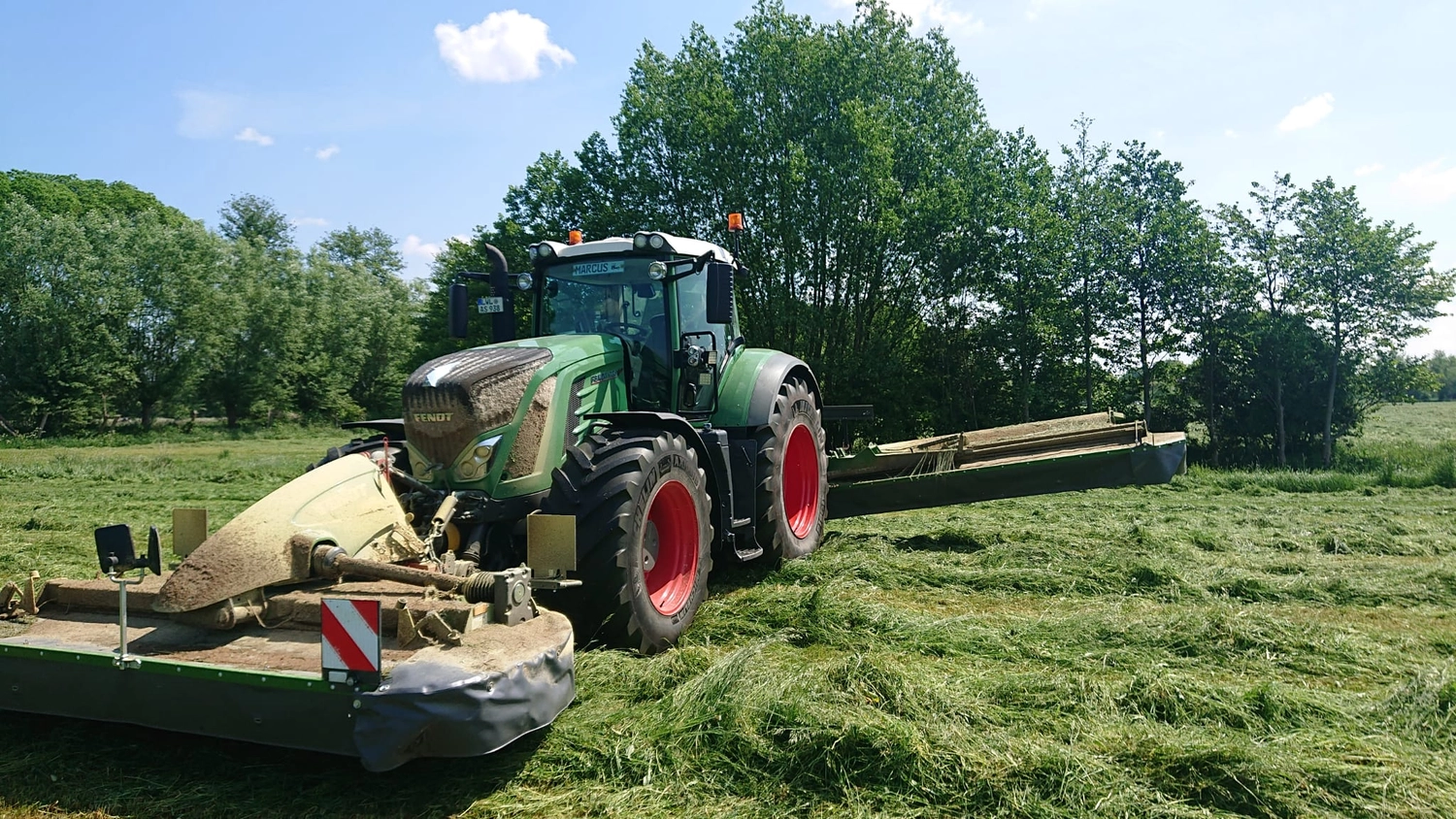 Agrargemeinschaft Holthusen e.G. - Landwirtschaftlicher - Fendt 724 Vario Traktor mit Mähaufbereiter-Anbaugerät für die landwirtschaftliche Ernte.